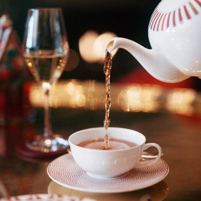 Afternoon Tea wird aus einer Porzellankanne in eine Teetasse eingeschenkt