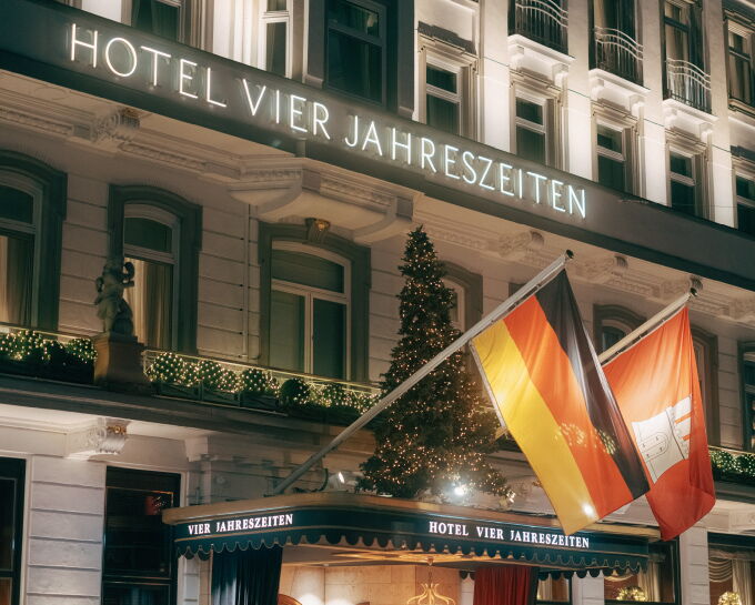 Festively decorated facade of Hotel Vier Jahreszeiten Hamburg with an illuminated Christmas tree