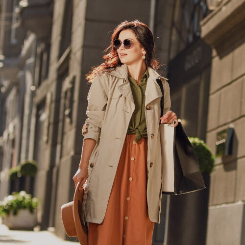 Elegant woman with a shopping bag on her right arm walking along the street