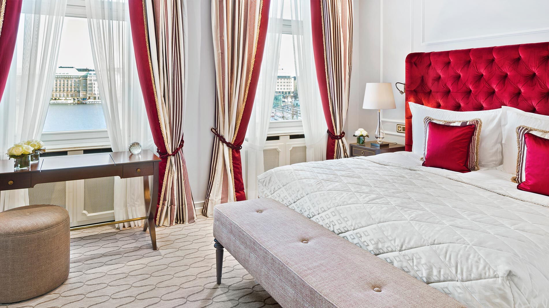 Das rot akzentuierte Schlafzimmer mit Aussicht auf die Binnenalster im Hotel Vier Jahreszeiten in Hamburg