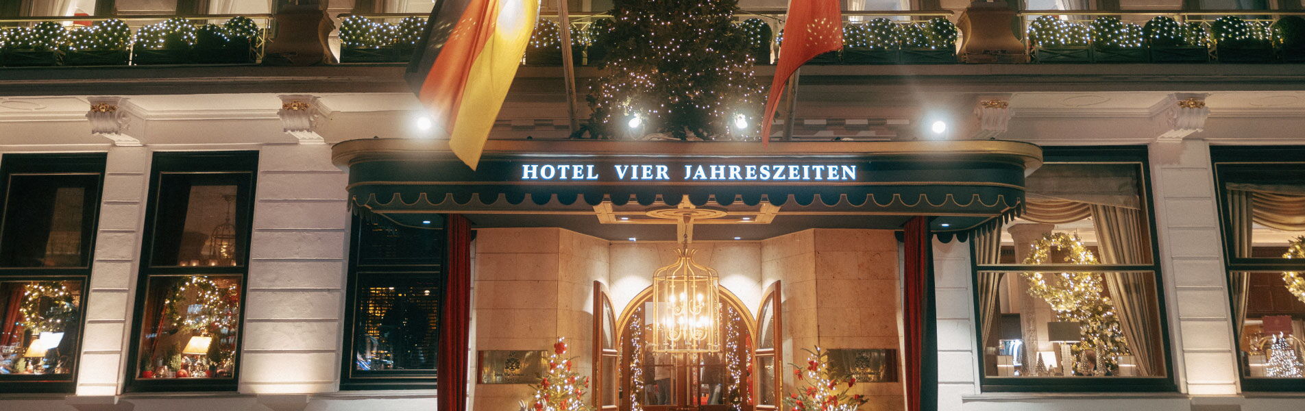 Festively decorated entrance of Hotel Vier Jahreszeiten Hamburg during Christmas season.