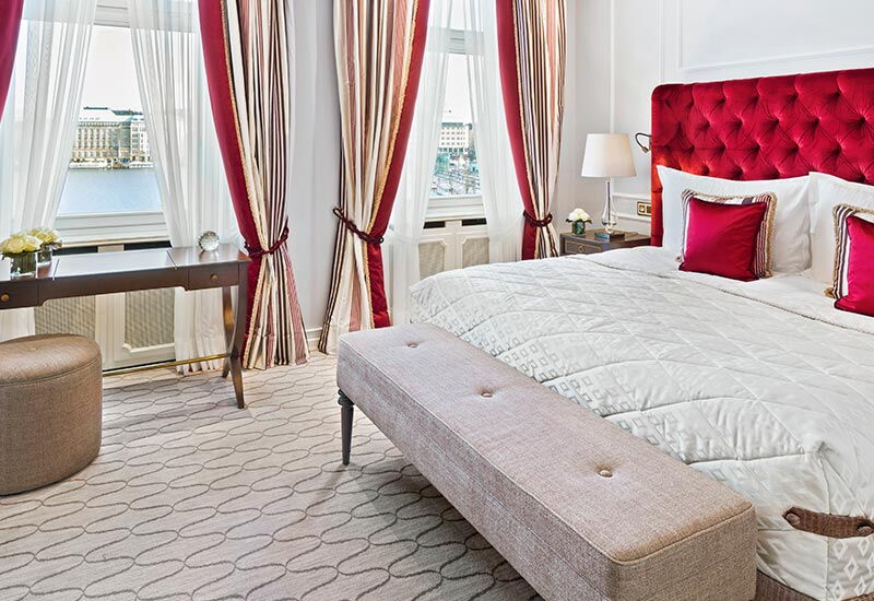 Der rot eingerichtete Schlafbereich im Doppelzimmer Alster Deluxe im Hotel Vier Jahreszeiten Hamburg
