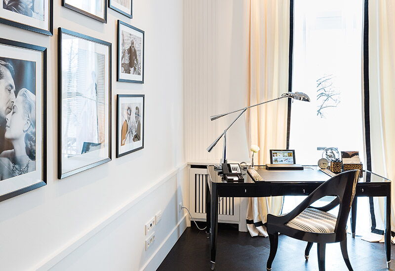 Ein Schreibtisch neben einer Galeriewand in der Ralph Lauren Suite im Hotel Vier Jahreszeiten in Hamburg