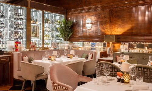 Eleganter Innenbereich des Restaurants The Grill im Hotel Vier Jahreszeiten mit gedeckten Tischen, warmem Holzinterieur und stimmungsvoller Beleuchtung.