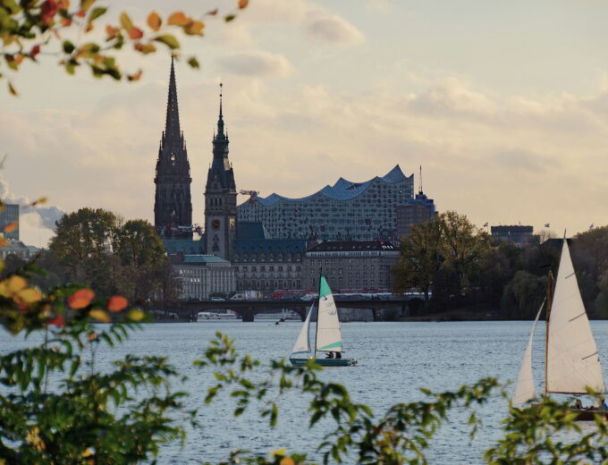 Blick über die Außenalster auf Elbphilharmonie und Hamburger Skyline mit Segelbooten.