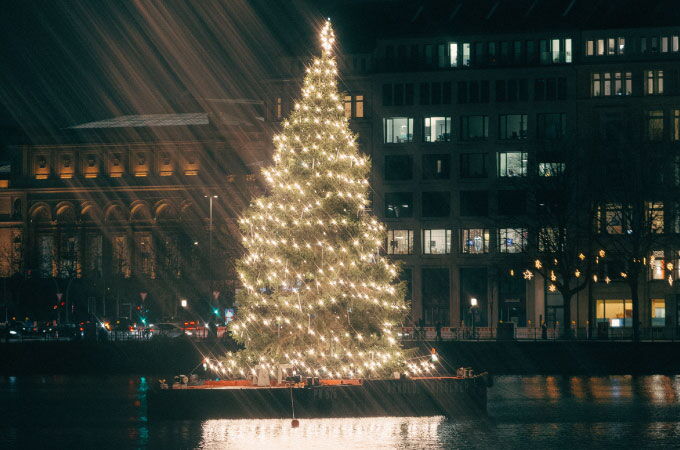 Festively illuminated Christmas tree on the Binnenalster near Hotel Vier Jahreszeiten Hamburg.