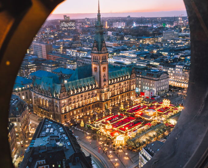 View of the festively illuminated Christmas market at Hamburg City Hall during Advent season.