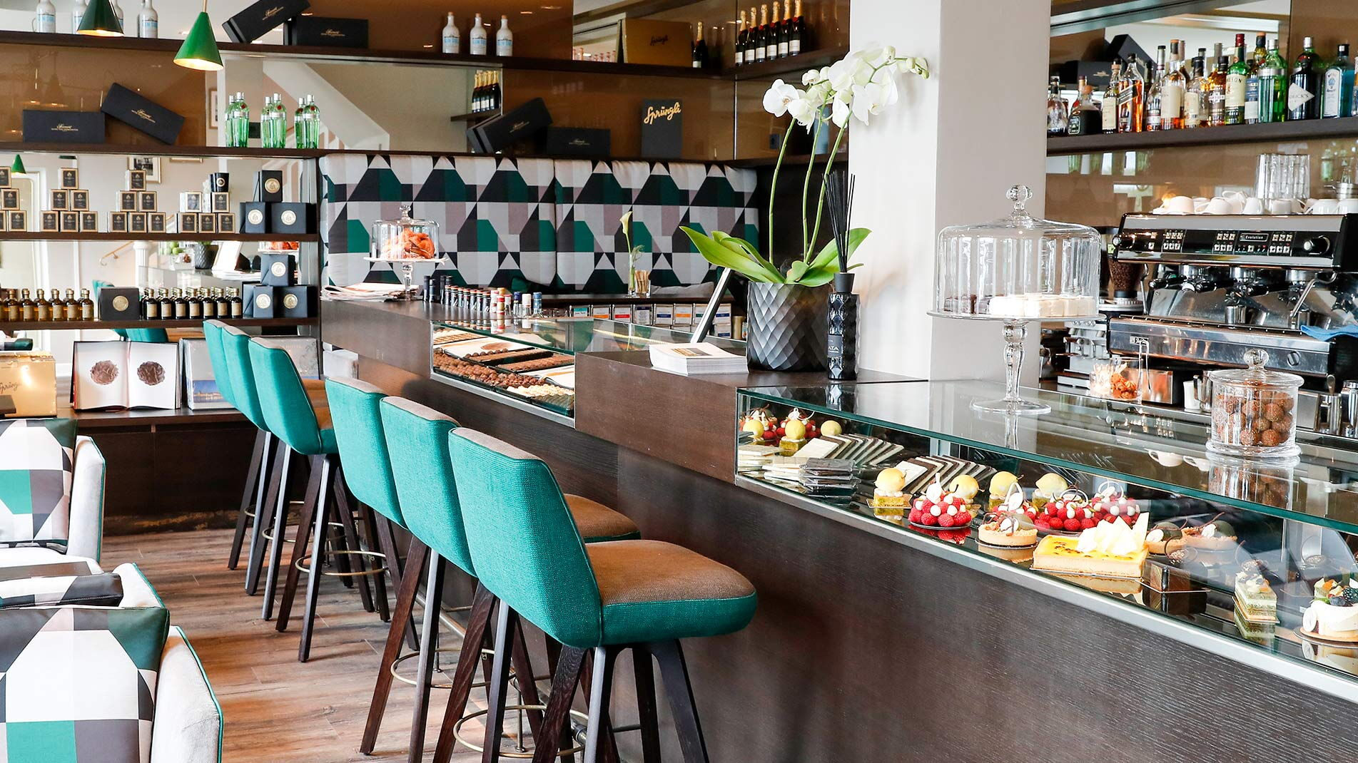 Die Theke und Bar der Condi Lounge mit türkisen Barhockern im Hotel Vier Jahreszeiten in Hamburg
