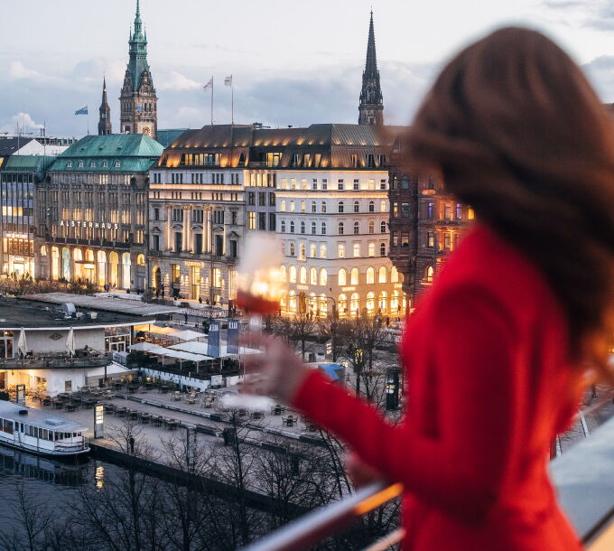 Frau in rotem Kleid auf dem Dach des Hotel Vier Jahreszeiten Hamburg mit Blick über die Binnenalster