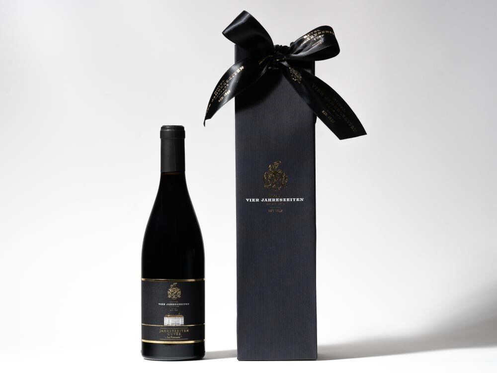 Rotwein Le Ponnant in einer schwarzen Flasche neben einer Geschenkverpackung - ein Produkt des Hotel Vier Jahreszeiten in Hamburg