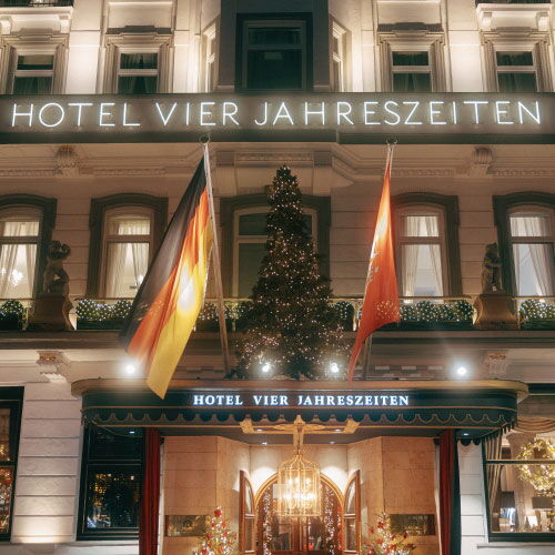 Festively decorated entrance of Hotel Vier Jahreszeiten Hamburg during Christmas season.