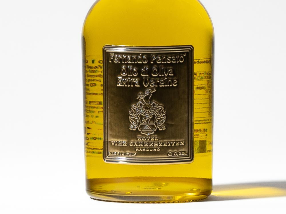 Nahaufnahme des Etiketts des Olivenöl Single (0,25 l) - ein Produkt des Hotel Vier Jahreszeiten in Hamburg