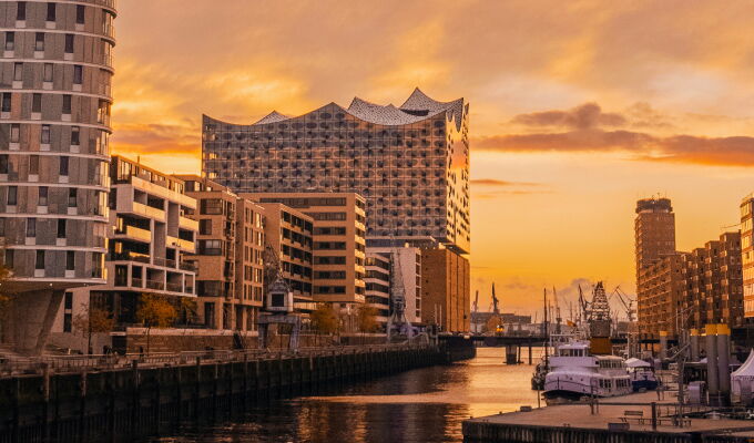 Blick auf die Elbphilharmonie und den Hamburger Hafen bei leuchtendem Sonnenuntergang