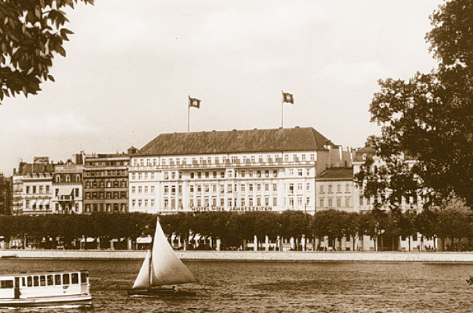 Old exterior view of the Hotel Vier Jahreszeiten photographed across the Inner Alster.