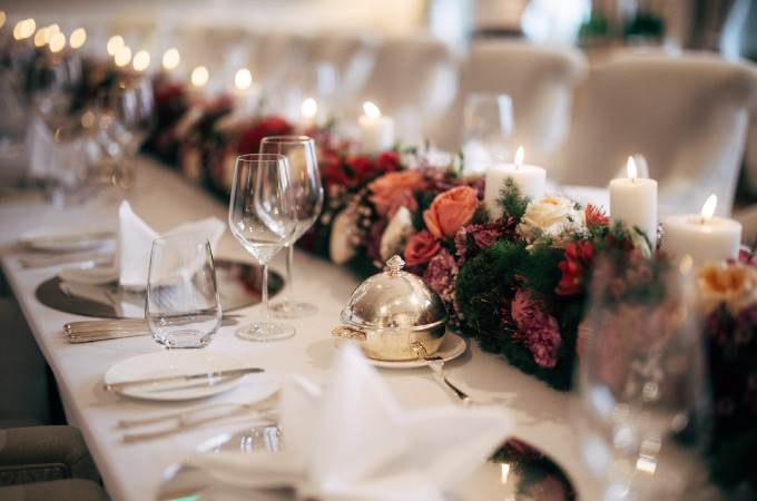 Elegantly laid table with high-quality floral arrangement and white candles in the centre of the table