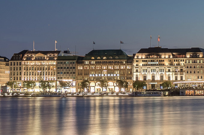Inner Alster photographed in the evening with illuminated buildings such as the Alsterhaus in the background