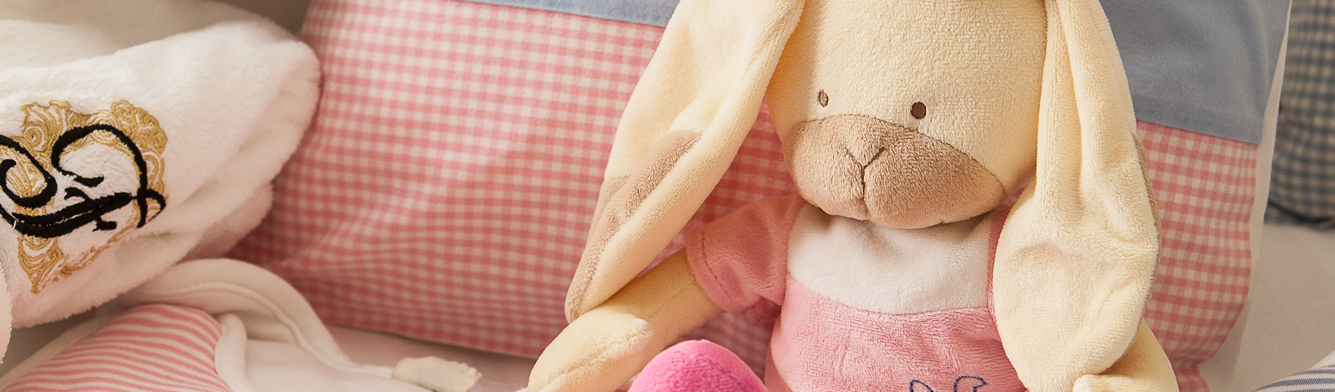 Kuscheltier Hase auf einem rosa Kissen neben einem Handtuch des Hotel Vier Jahreszeiten in Hamburg