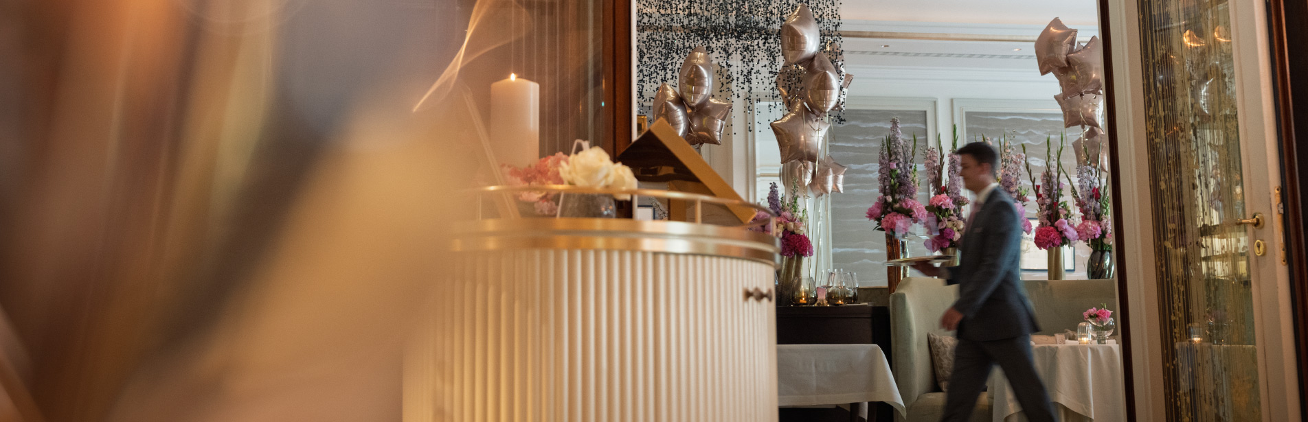Empfangsbereich des Restaurant Haerlin im Hotel Vier Jahreszeiten Hamburg mit Kerze und Blumendekoration.